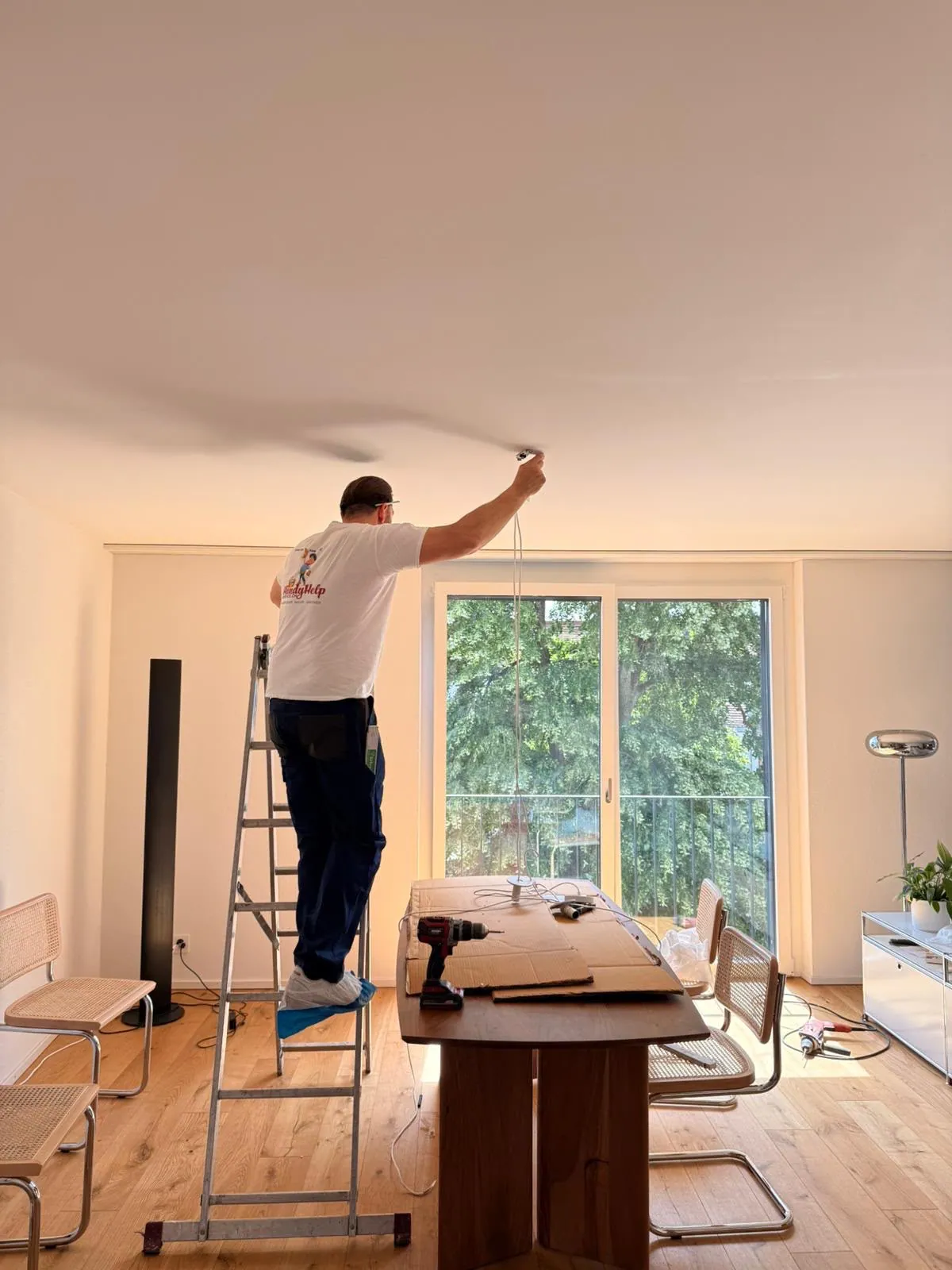 Mitarbeiter montiert eine Deckenleuchte